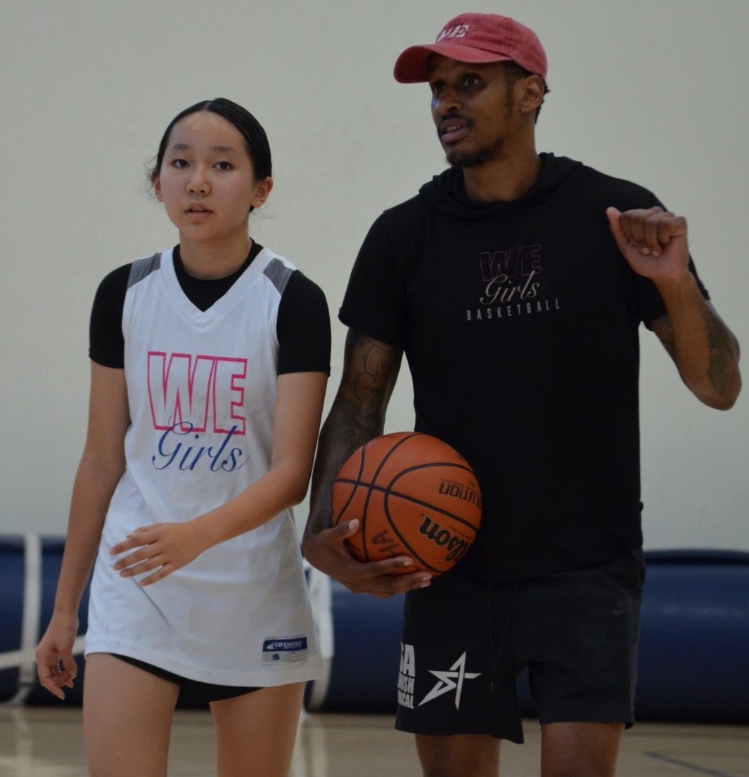 A WE coach guiding a young player through a drill
